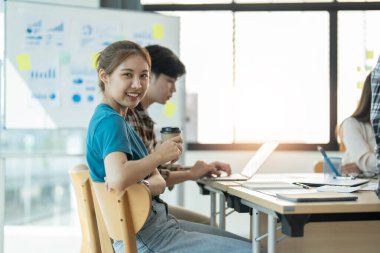 Bir grup Asyalı genç yaratıcı mutlu kahkaha atmaktan ve büyük başarı duygusundan heyecan duymaktan, takım çalışmasından iş dünyasına atılmaktan iş dünyasının gelişigüzel gelişen beyin fırtınası bürosundan keyif alır.