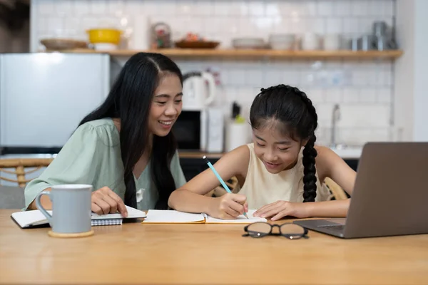 Az anya és az ázsiai kislány laptopon tanulnak, házi feladatot készítenek, ismereteket tanulnak az online oktatási e-learning rendszerben. gyermekek videó konferencia tanár tutor otthon — Stock Fotó