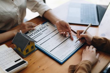 Emlakçılar sigorta kontratının imzalandığına işaret ediyor ve ofisteki müşterilere açıklıyorlar.