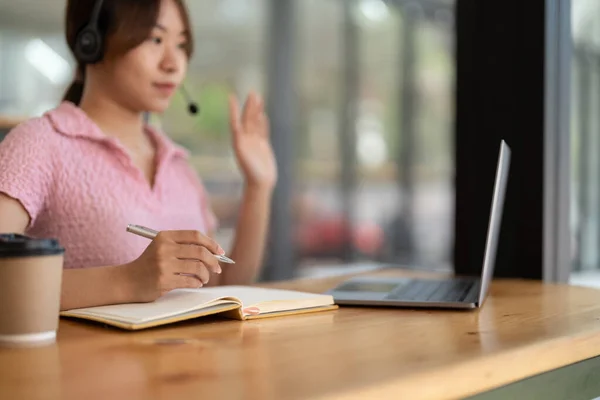 Jovem mulher asiática fazendo anotações enquanto ouve webinar online em casa, usando fone de ouvido, usando laptop para aprender língua estrangeira, conceito de e-learning, ficar em casa durante a quarentena — Fotografia de Stock