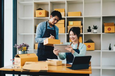 Asyalı çift evde online iş yapıyor. Ürünleri karton kutulara koymaya yardım etmek. Aile kavramı, modern iş, küçük girişimciler, çevrimiçi dağıtım