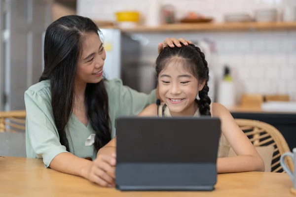 Boldog anya fiatal lányával élvezi az online vásárlást vagy az otthoni munkát. Üzleti távolból és virtuális kommunikáció a családdal és a barátokkal. — Stock Fotó
