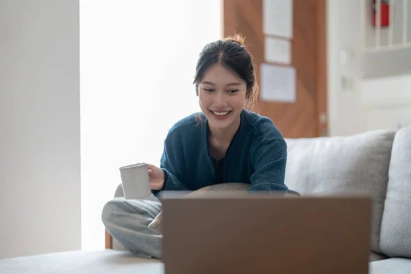 Glückliche junge asiatische Frau mit Laptop-Computer auf gemütlichem Sofa, Sonntagmorgen Konzept — Stockfoto