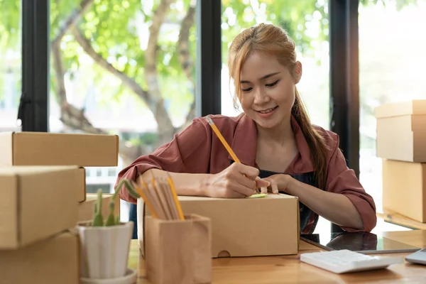 在网上购物 创业小企业主在工作场所的纸板箱上写下地址 亚洲女企业家在国内与盒子打交道的中小型企业 — 图库照片