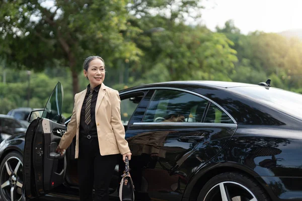 アジアの成熟したビジネス成功の女性が高級車を降りる — ストック写真