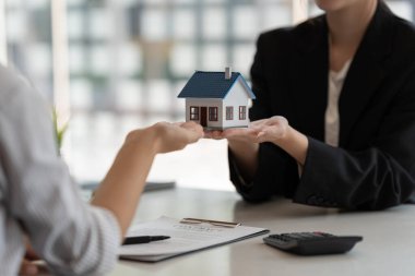 Emlakçılar bir ev almayı ve ev modelini ajanstaki müşterilerine vermeyi kabul ediyorlar. Kavram anlaşması.