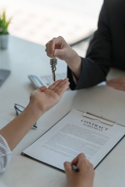 Emlakçı, ofiste sözleşme imzaladıktan sonra müşterisinin ev anahtarını tutuyor. Gayrimenkul konsepti, eve taşınma ya da mülk kiralama..