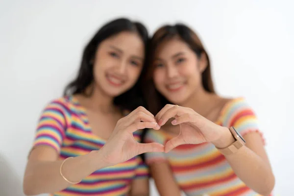 アジアの愛情感情レズビアンカップルの女性ロマンチックな日付指の心の形を作るシンボルリーンヘッド愛好家の目は虹の中にカジュアルなTシャツを着て閉じ — ストック写真