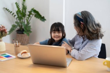 Büyükannesi olan küçük bir kız dizüstü bilgisayar kullanıyor, evde sanal online derste öğreniyor.