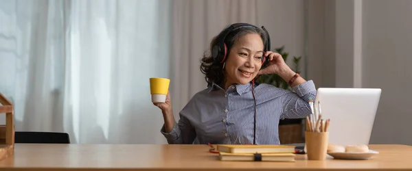 Счастливая Старшая Азиатка Наушниках Слушает Песни Ноутбуке Гостиной Уютном Доме — стоковое фото