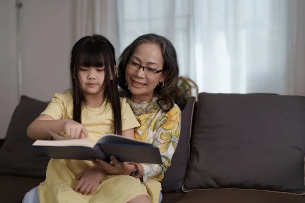 快乐的亚洲家庭祖母在家给孙女读书 — 图库照片