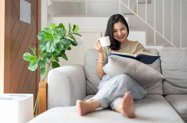 Glücklich Asiatische Junge Frau Sitzt Auf Dem Sofa Und Liest — Stockfoto