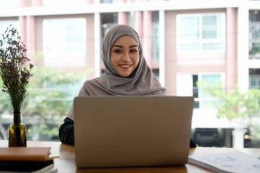 Dizüstü bilgisayarla çalışan Asyalı Müslüman kadın yönetici portresi