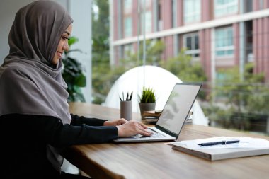 Mutlu güzel Müslüman iş kadını kahverengi tesettür finans hakkında çalışıyor iş raporu modern ofis.