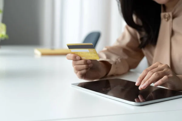 Close up woman holding bank credit card and type on digital tablet for shopping online, buying goods or ordering online, entering bank accounts and details in online banking offer