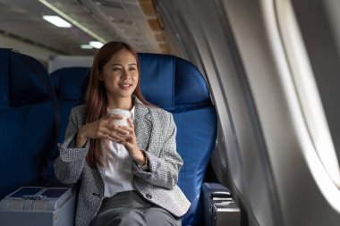 Genç Asyalı kadın hava uçağı, seyahat ve ulaşım kavramı pencereye bakıyor.