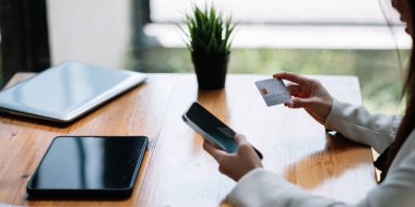 Kredi kartı tutan ve online alışveriş için akıllı telefon kullanan genç bir kadın. Çevrimiçi ödeme alışveriş konsepti. kopyalama alanı afişi.