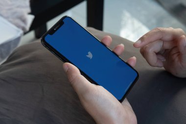 CHIANG MAI, THAILAND - FEB.12, 2022: Elma iPhone X 'i tutan kadın tren istasyonunda Twitter uygulaması ekranda. Twitter uygulaması, Twitter çevrimiçi bir sosyal ağdır.
