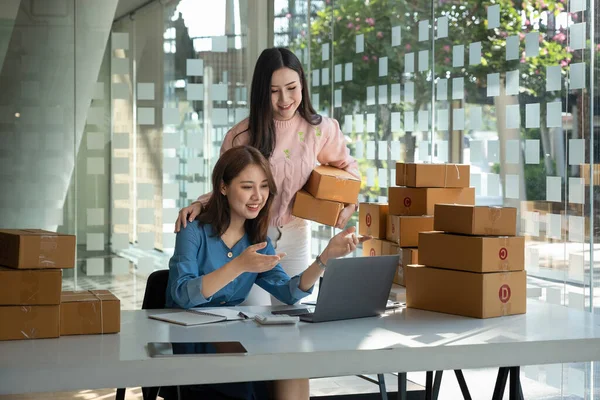 startup small business owner working at workplace. two asian wooman freelance seller check product order for delivery. Online selling, e-commerce, shipping concept.