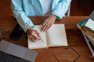 Bir kadının not defterine not tutarken ya da içerideki bilgisayarlarda çalışırken ya da öğrenirken en iyi görüntüsü. Eğitim kursu, seminer, eğitim, çevrimiçi eğitim konsepti.