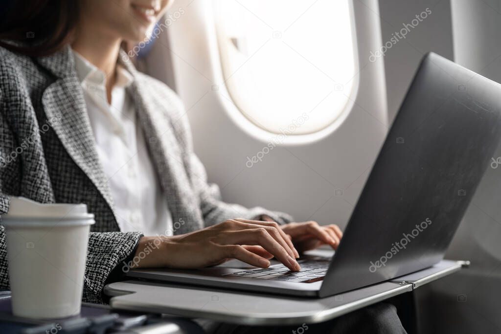 Close up hand of business asian woman uses laptop while flying on airplane near window