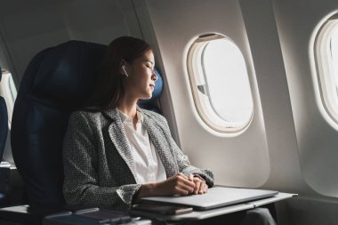 Yorgun Asyalı kadın uçakla seyahat ederken koltukta kestiriyor. Uçaklarla ticari ulaşım.