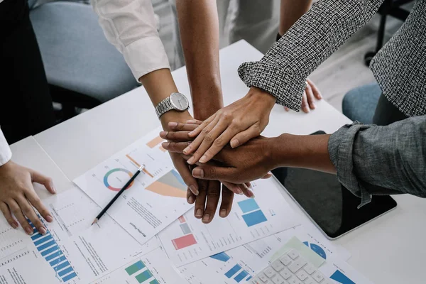 Close up happy diverse business people putting hands together, showing support and unity. Multiracial colleagues involved in team building activity. Staff training concept, start working together