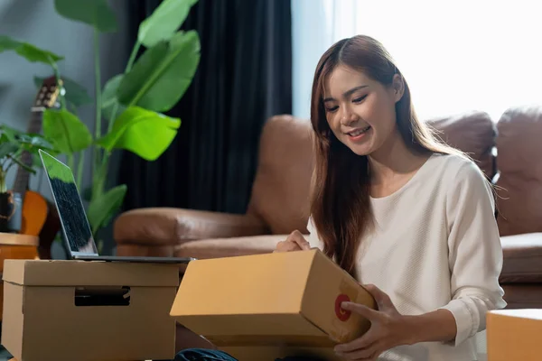 Small business parcel for shipment to client, Young asian woman received online shopping parcel opening boxes and buying items by credit card, online marketing on purchase order package product.