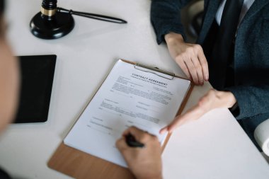 Avukat hukuk danışmanı müvekkiline tokmak ve hukuk hukuku ile imzalanmış bir sözleşme sunar. Adalet ve Avukat İş ortaklığı toplantısı konsepti