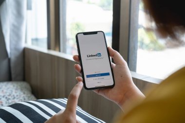 CHIANG MAI, THAILAND, JUL 12, 2022: Bir kadın ekranda LinkedIn uygulamalı Apple iPhone X 'leri tutuyor. LinkedIn akıllı telefonlar için bir fotoğraf paylaşım uygulaması