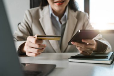 Kredi kartı ve akıllı telefonu tutan kadınların ellerini kapat. İnternetten ödeme yapan genç bir kadın. Bankacılık hizmetini kullanan, bilgi giren, alışveriş yapan, internet mağazasından sipariş veren, güvenli ödeme yapan bir kadın..