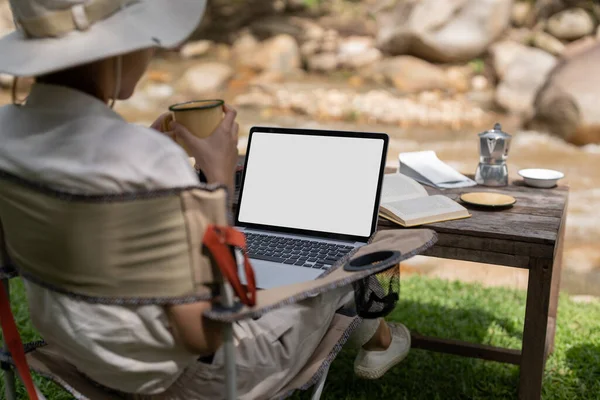 Young girl using laptop in camping tent, hiking in forest. laptop blank white screen for advertising.