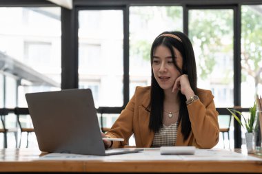 Portrait of asian business woman paying bills online with laptop in office. Beautiful girl with computer and chequebook, happy paying bills. Startup business financial calculate account concept