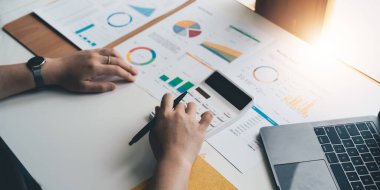 Modern ofis, finans ve iş konseptinde grafik grafik grafiği ve hesap makinesiyle çalışan ve finansal raporları analiz eden Asyalı muhasebeci.
