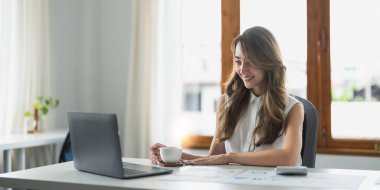 Mutlu Asyalı kadın kişisel gider yönetimi ile meşgul bir masada oturuyor, hesap makinesi kullanıyor ev hizmetlerini hesaplıyor, güvenli e-bankacılık uygulaması aracılığıyla faturaları ödüyor. Ekonomi, muhasebe kavramı.