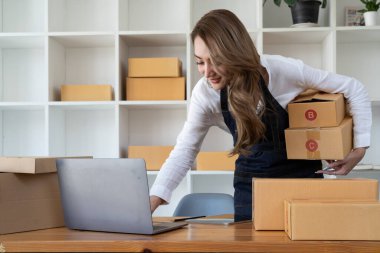 Küçük bir Asyalı girişimci kadın girişimcinin portresi. Müşteri ile birlikte bir iç kutuya koymadan önce sarı bir gömlek alıyor. Çevrimiçi İş Fikirleri ve Serbest Çalışmalar.