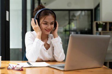 Online education, e-learning. young woman studying remotely, using a laptop, listening to online webinar at home.