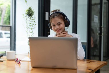 Online education, e-learning. young woman studying remotely, using a laptop, listening to online webinar at home.