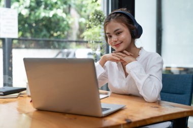 Online education, e-learning. young woman studying remotely, using a laptop, listening to online webinar at home.