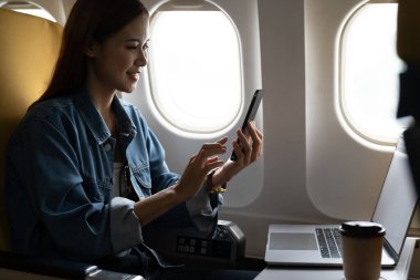 Beautiful asian travel woman using mobile phone in airplane