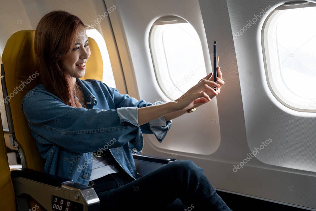 Beautiful Asian woman take a selfie with mobile phone in airplane.