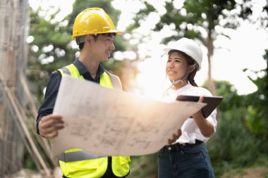 Mühendislik ve inşaat yöneticileri proje mavi baskı inşaat sahasında masada tartışıyor.