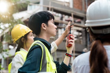 Mühendislik ve inşaat yöneticileri proje mavi baskı inşaat sahasında masada tartışıyor.