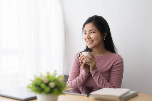 Portrait cheerful asian woman with a cup of coffee during studying online learning