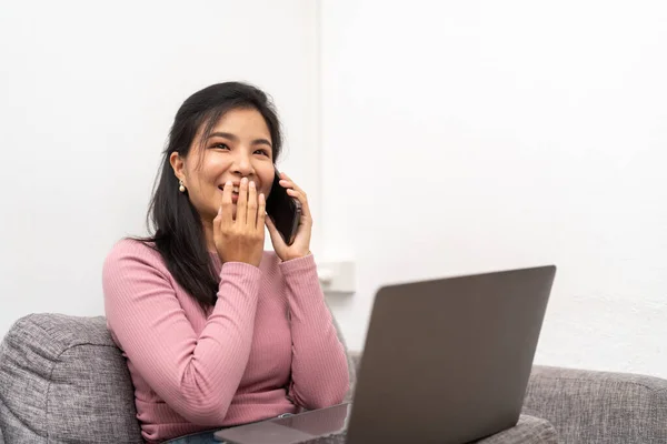 Asian female laughing telling funny story by phone to friend.