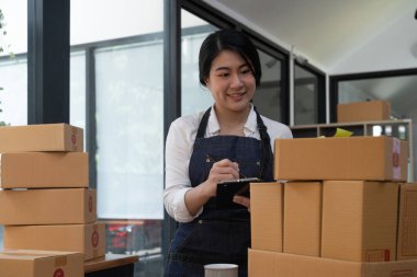 Asian young woman working with a box at home the workplace. start-up small business owner, small business entrepreneur SME or freelance business online and delivery concept