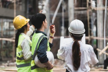 Mühendislik ve inşaat yöneticileri proje mavi baskı inşaat sahasında masada tartışıyor.