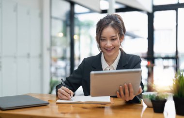 businesswoman using digital tablet and pen to take notes at office