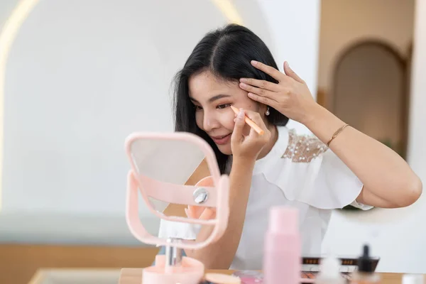 Beauty blogger concept, beautiful and cute asian young woman, girl makeup face by applying brush for eyes on eyebrow, eyeshadow looking at the mirror at home. Female look with natural fashion style