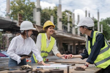 Three colleagues discussing data working and tablet, laptop with on on architectural project at construction site.